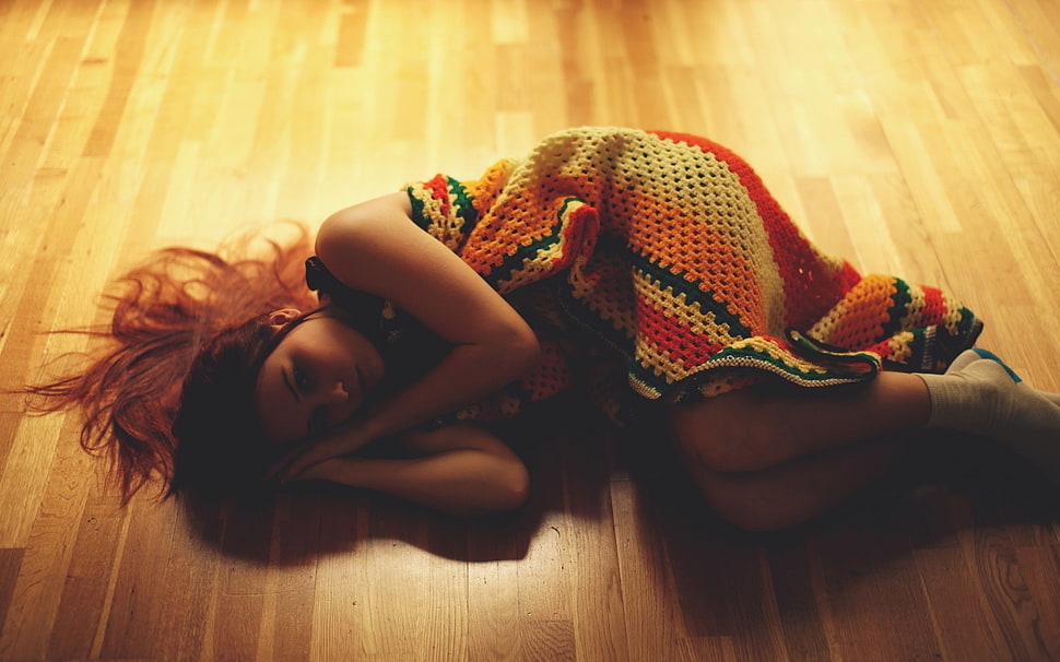 woman lying on brown wooden floor wearing white, orange, and red knit dress HD wallpaper